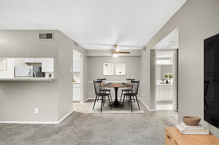 Elegant open-plan living and dining area with modern kitchen pass-through, stylish decor, and contemporary lighting.