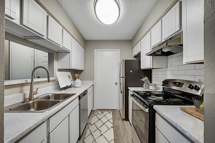 Modern galley kitchen with sleek countertops, white cabinetry, and stainless steel appliances, exuding a contemporary charm.