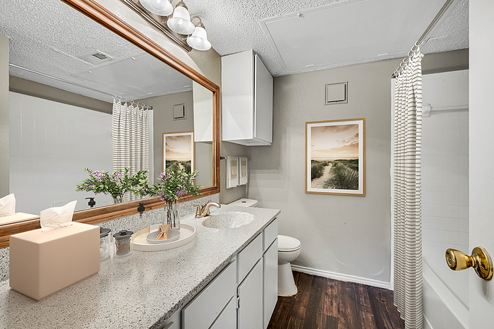 Elegant bathroom featuring a large mirror, sleek countertops, and tasteful decor, offering a serene and modern atmosphere.