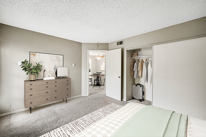 Bright and inviting bedroom with modern dresser, spacious closet, and a glimpse of the stylish dining area.