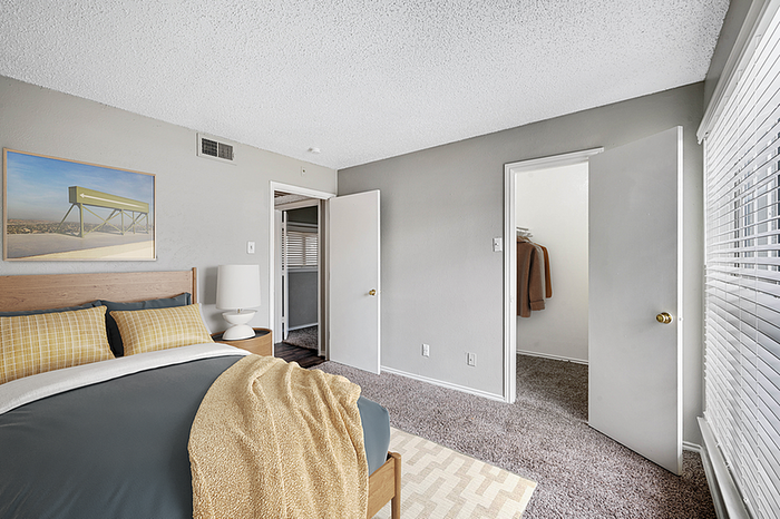 Inviting bedroom with cozy bed, stylish decor, and ample natural light from large windows.