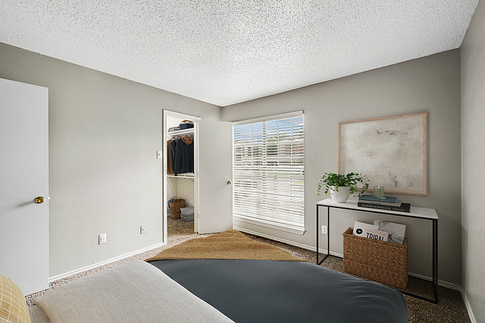 Bright and inviting bedroom with large window, plush carpet, and a cozy walk-in closet, ideal for relaxing and organizing.