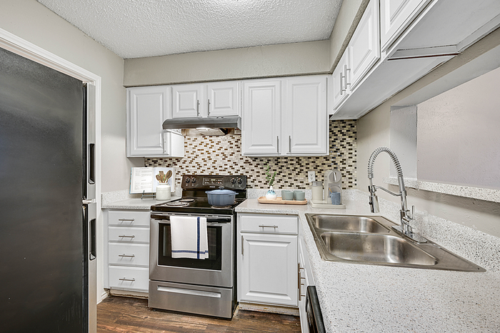 Modern kitchen with sleek stainless-steel appliances, elegant white cabinetry, and a stylish mosaic tile backsplash.