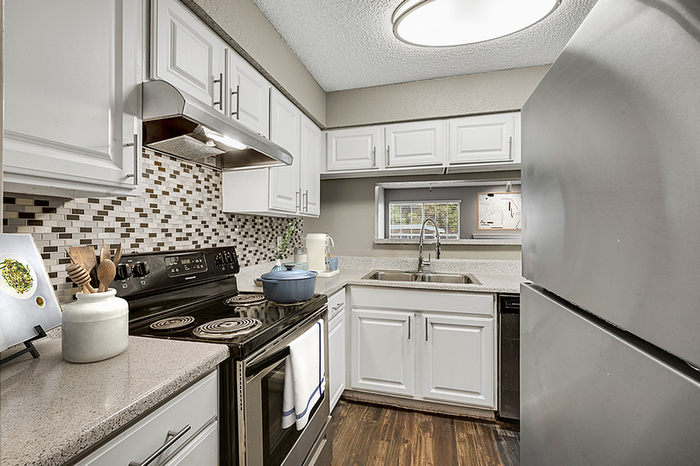 Modern kitchen with elegant white cabinetry, sleek stainless steel appliances, and stylish mosaic backsplash.