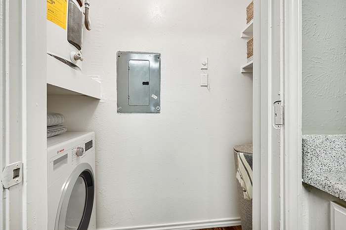 Compact laundry nook with modern washer, neatly organized with shelves and storage solutions.