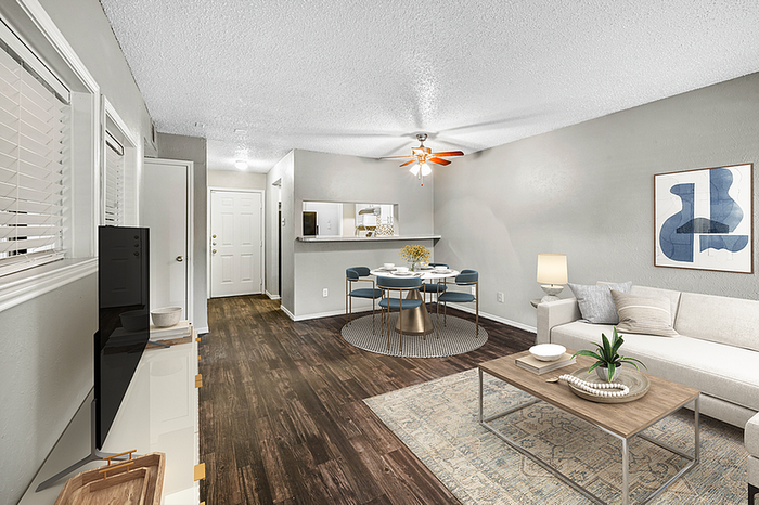Chic living room with modern decor and open dining area, featuring sleek hardwood floors and stylish neutral walls.