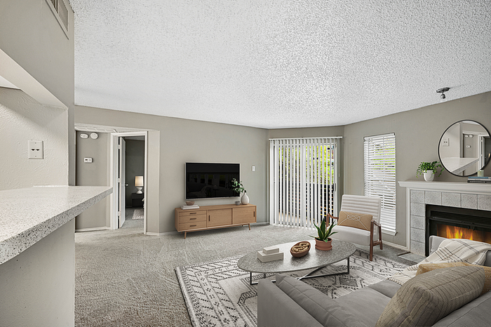 Inviting living room with a cozy fireplace, modern decor, and abundant natural light from large windows and sliding doors.