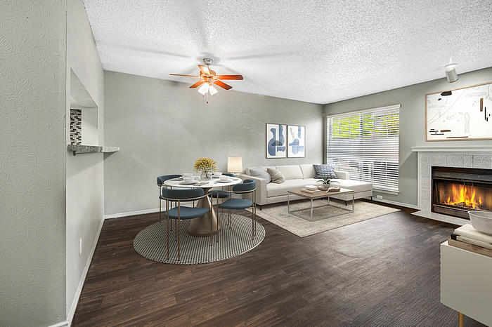 Inviting living and dining area with elegant hardwood flooring, cozy fireplace, and abundant natural light from large windows.