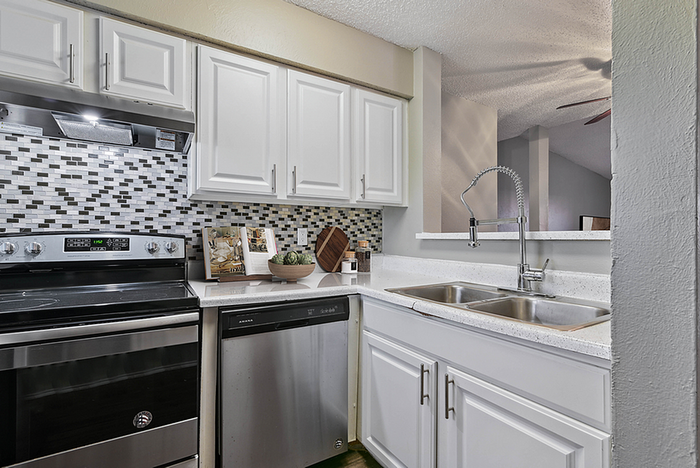 Modern kitchen with sleek stainless steel appliances, elegant mosaic backsplash, and white cabinetry for a bright, inviting space.