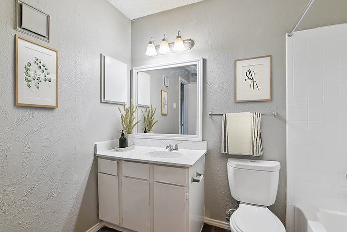 Contemporary bathroom featuring elegant decor, modern vanity with a sleek countertop, and framed artwork enhancing the serene atmosphere.