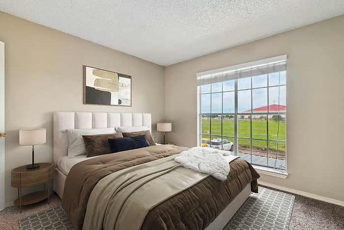 Bright and inviting bedroom with a cozy double bed, elegant decor, and a large window offering scenic views of the green landscape.