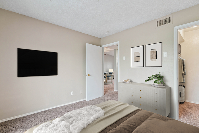 Elegant bedroom with a plush bed, modern artwork, and a spacious walk-in closet offering a cozy yet stylish living space.