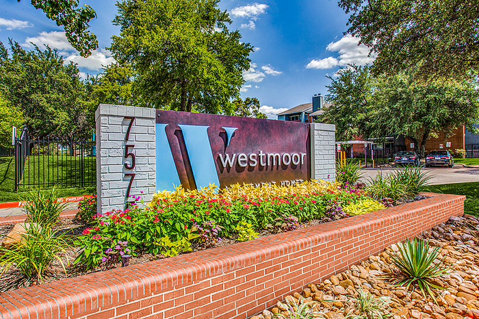 Inviting entrance to Westmoor Apartments with vibrant landscaping and bold signage, enhancing the community's welcoming ambiance.