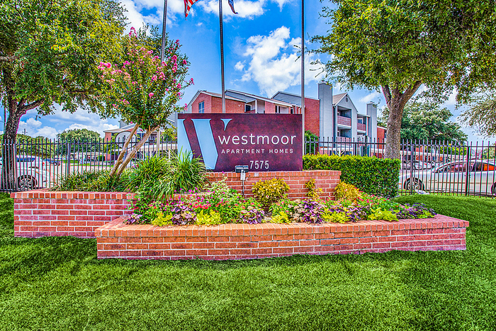 Charming Westmoor Apartment Homes entrance with vibrant floral landscaping and welcoming sign.