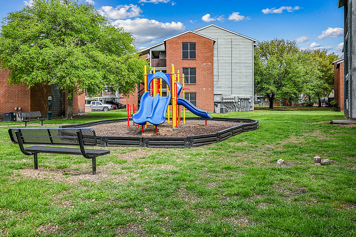 Inviting outdoor playground with vibrant blue slide, set in a well-maintained green space, perfect for family-friendly living.