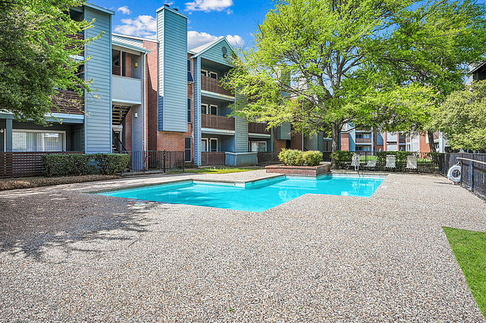 Inviting apartment exterior with a sparkling swimming pool and lush green surroundings.