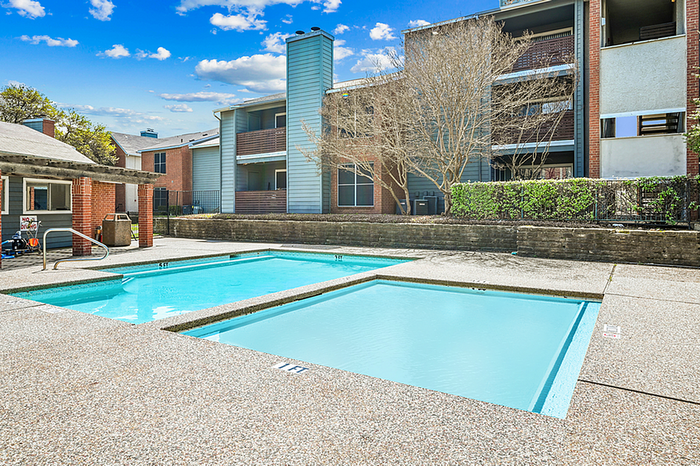 Inviting apartment complex boasting a pristine outdoor pool under a vibrant blue sky, perfect for relaxation and leisure.
