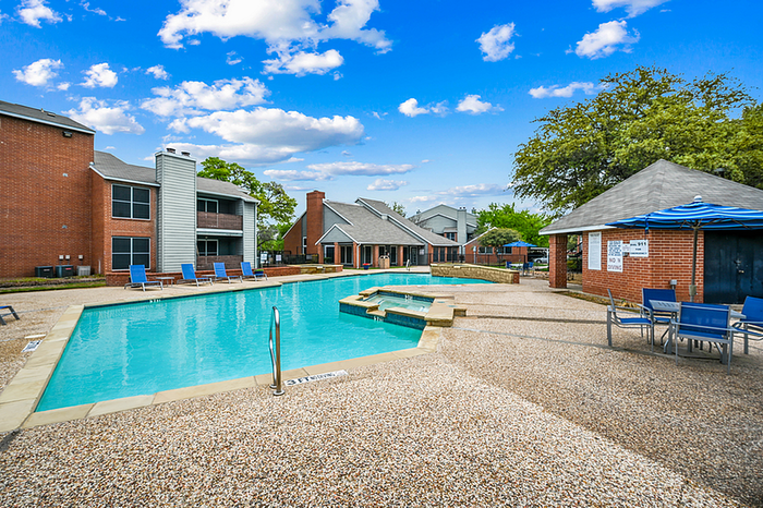 Inviting apartment complex with a sparkling swimming pool, cozy lounging areas, and vibrant blue skies.