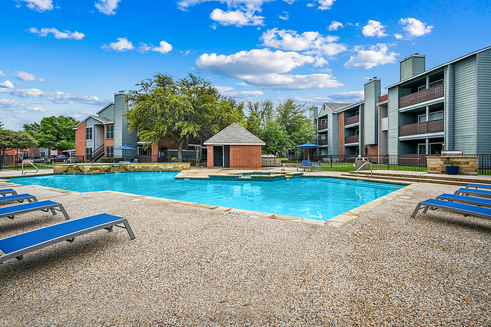 Inviting apartment community with a sparkling outdoor pool surrounded by comfortable lounge chairs and lush greenery.
