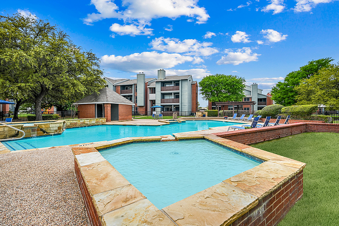 Inviting apartment community featuring a stunning pool area, surrounded by lush greenery and modern architecture under a bright blue sky.