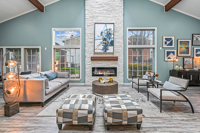 Inviting clubhouse with high ceilings, modern fireplace, and elegant decor featuring a cozy sofa and stylish armchairs.