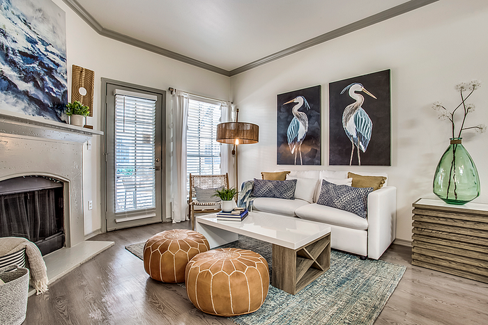 Chic living room with elegant decor, featuring a cozy white sofa, artistic bird paintings, and a warm fireplace ambiance.