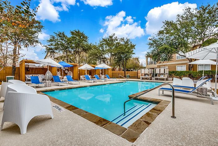 Inviting outdoor pool area with modern lounge chairs, shade umbrellas, and vibrant greenery, perfect for relaxation and social gatherings.