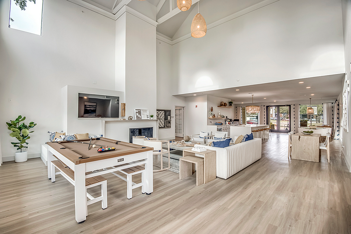 Expansive modern living area with high ceilings, elegant decor, and a pool table, blending style with open-concept luxury.