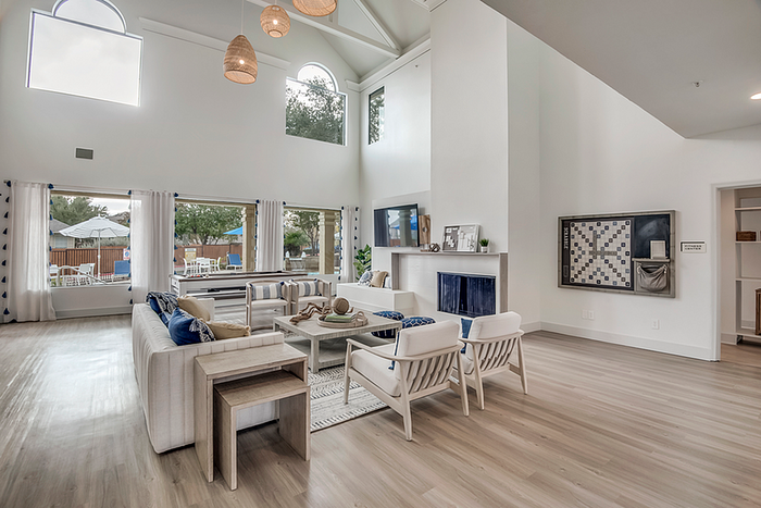 Luxurious open-concept living room with high ceilings, modern decor, and large windows offering natural light and outdoor views.