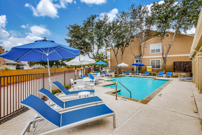 Inviting swimming pool area with vibrant blue lounge chairs and umbrellas, perfect for relaxation and enjoyment.