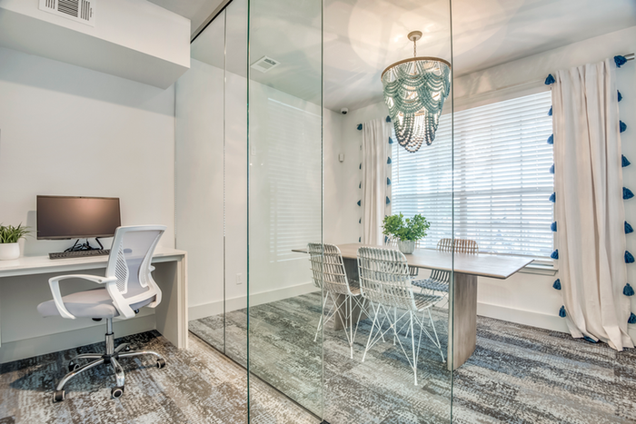 Business Center with glass wall, elegant chandelier, modern desk, and bright natural lighting.