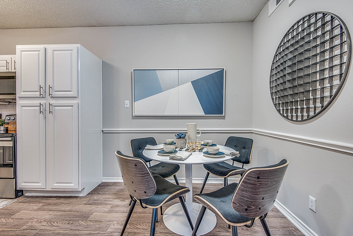 Chic dining area with a modern round table, stylish chairs, and contemporary wall art in an elegant apartment setting.