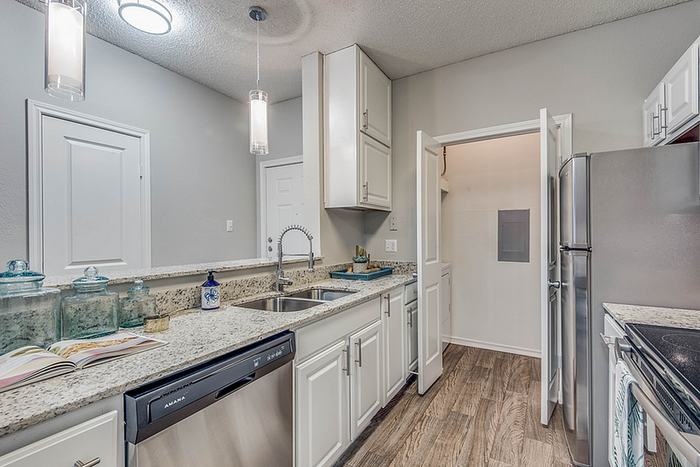Modern kitchen with sleek granite countertops, stainless steel appliances, and elegant pendant lighting for a stylish culinary experience.