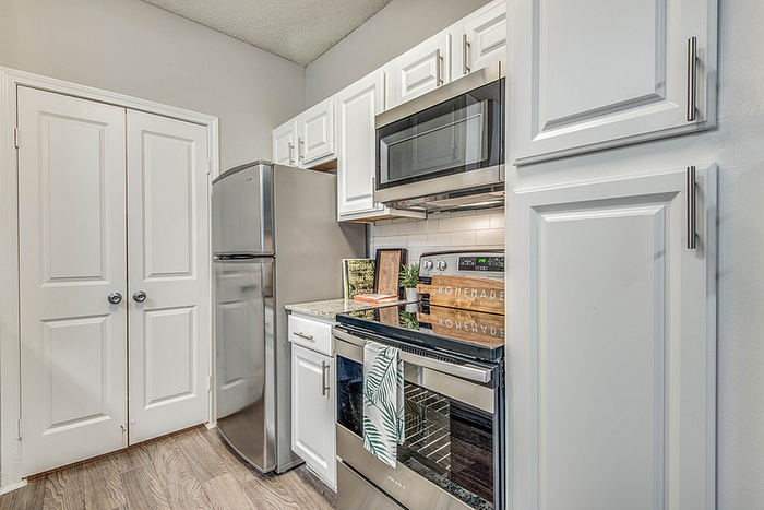 Modern kitchen with sleek stainless steel appliances, elegant white cabinetry, and chic backsplash, creating a stylish culinary space.