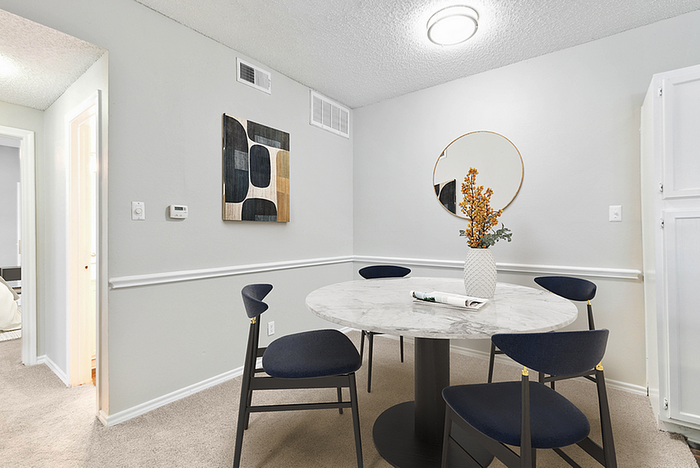 Chic dining area with a modern round marble table, stylish dark chairs, and minimalist decor, perfect for elegant gatherings.