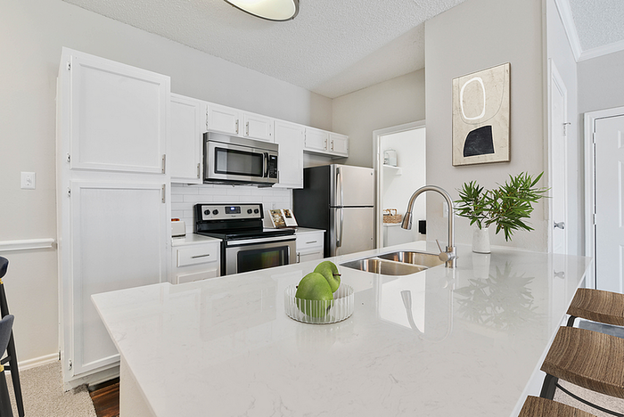 Bright, modern kitchen with sleek white cabinetry, stainless steel appliances, and a spacious marble island enhancing functionality and style.