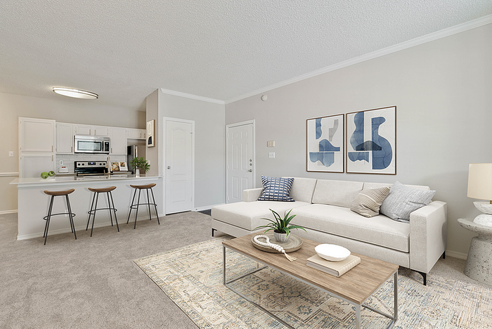 Modern open-concept living room with cozy seating, stylish decor, and a sleek kitchen with bar stools.