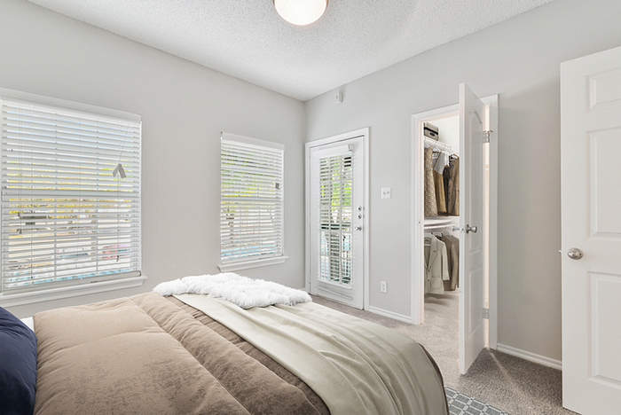 Bright bedroom with soft natural light, featuring a cozy bed, crisp white walls, and a spacious walk-in closet.