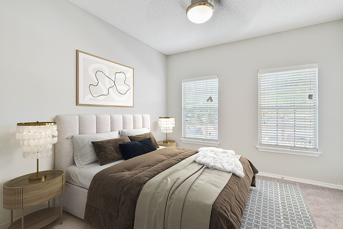 Inviting bedroom with plush bedding, chic decor, and abundant natural light from two windows, perfect for relaxation.