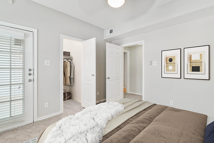 Modern bedroom with cozy decor, stylish artwork, and access to a bright balcony through glass doors.