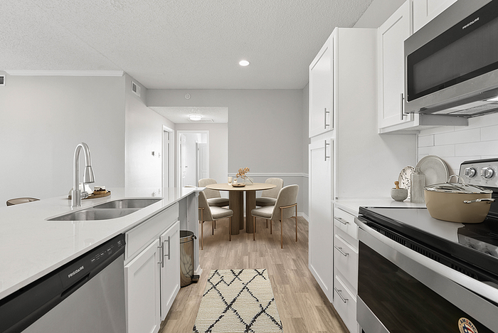 Modern kitchen with sleek countertops, stainless steel appliances, and an inviting dining area in a bright, open-layout apartment.