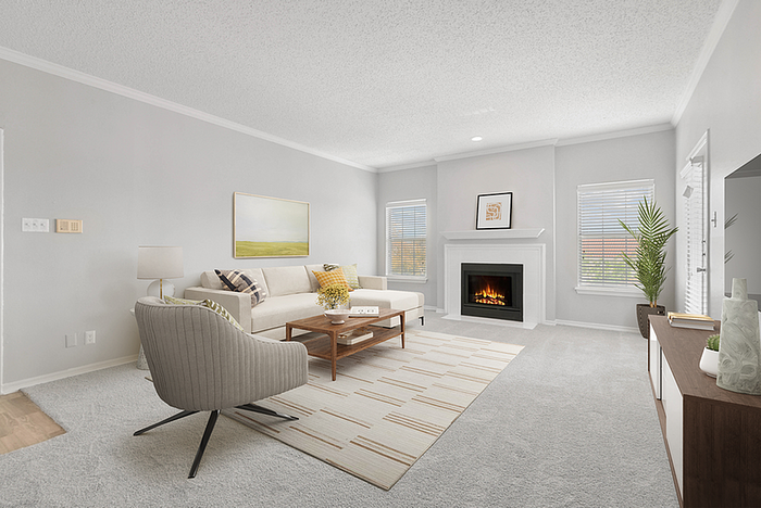 Elegant living room with modern decor, featuring a cozy fireplace, plush sofa, and chic armchair in a bright, inviting space.