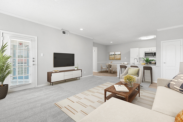 Bright and modern living area featuring an open floor plan, sleek kitchen with bar seating, and cozy sitting space with large windows.