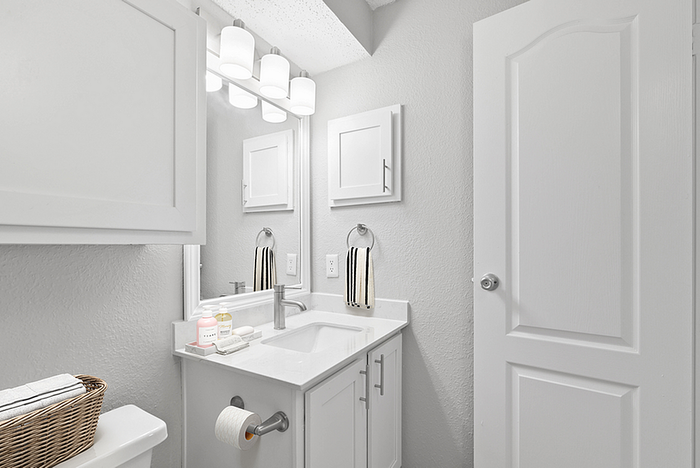 Sleek and modern bathroom with elegant lighting, pristine white cabinetry, and contemporary fixtures.