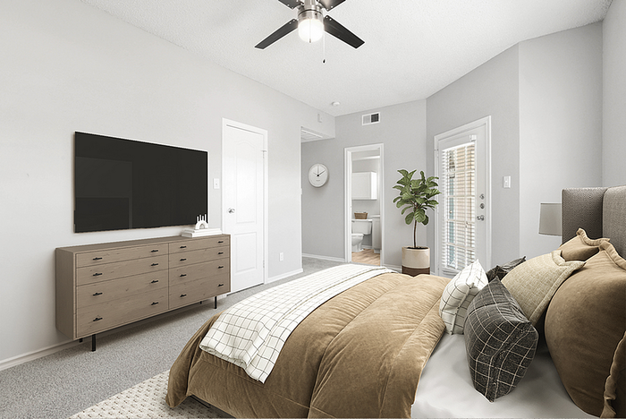 Bright and inviting bedroom showcasing modern decor, large TV, and a view of the adjoining bathroom and balcony.