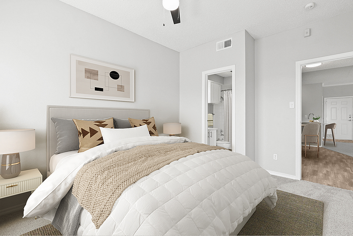 Bright, modern bedroom with cozy bedding, stylish decor, and an ensuite bathroom, leading to an inviting open-plan living area.