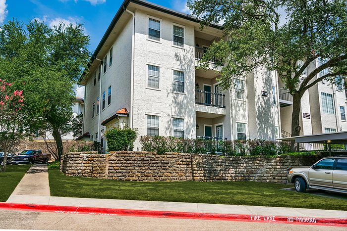 Charming apartment building with elegant balconies, lush greenery, and ample parking, perfect for modern urban living.