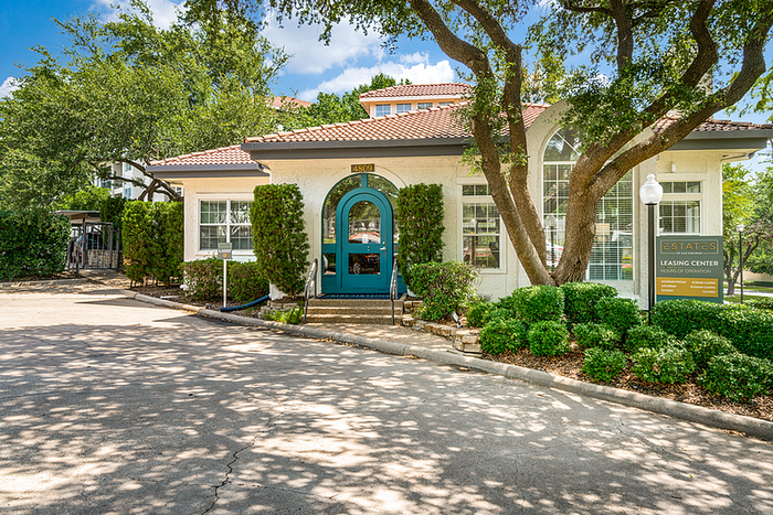 Charming leasing office with vibrant landscaping and inviting entrance under a sunny sky.