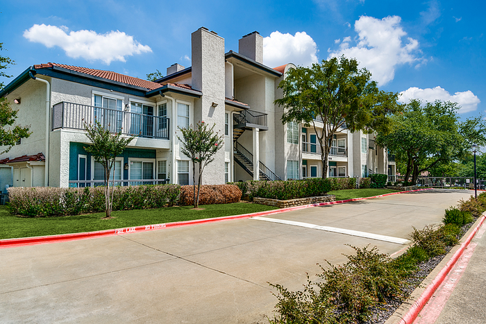 Elegant apartment community with modern architecture, private balconies, lush landscaping, and abundant natural light under a vibrant blue sky.