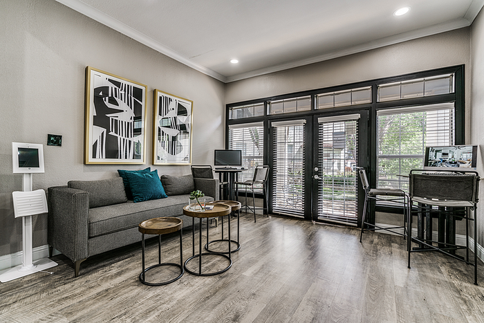 Contemporary clubhouse with elegant decor, featuring chic art pieces, a sleek gray sofa, and abundant natural light through large windows.